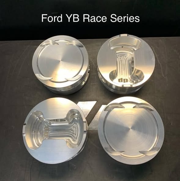 Four metal pistons arranged on a dark surface with 'Ford YB Race Series' text above.